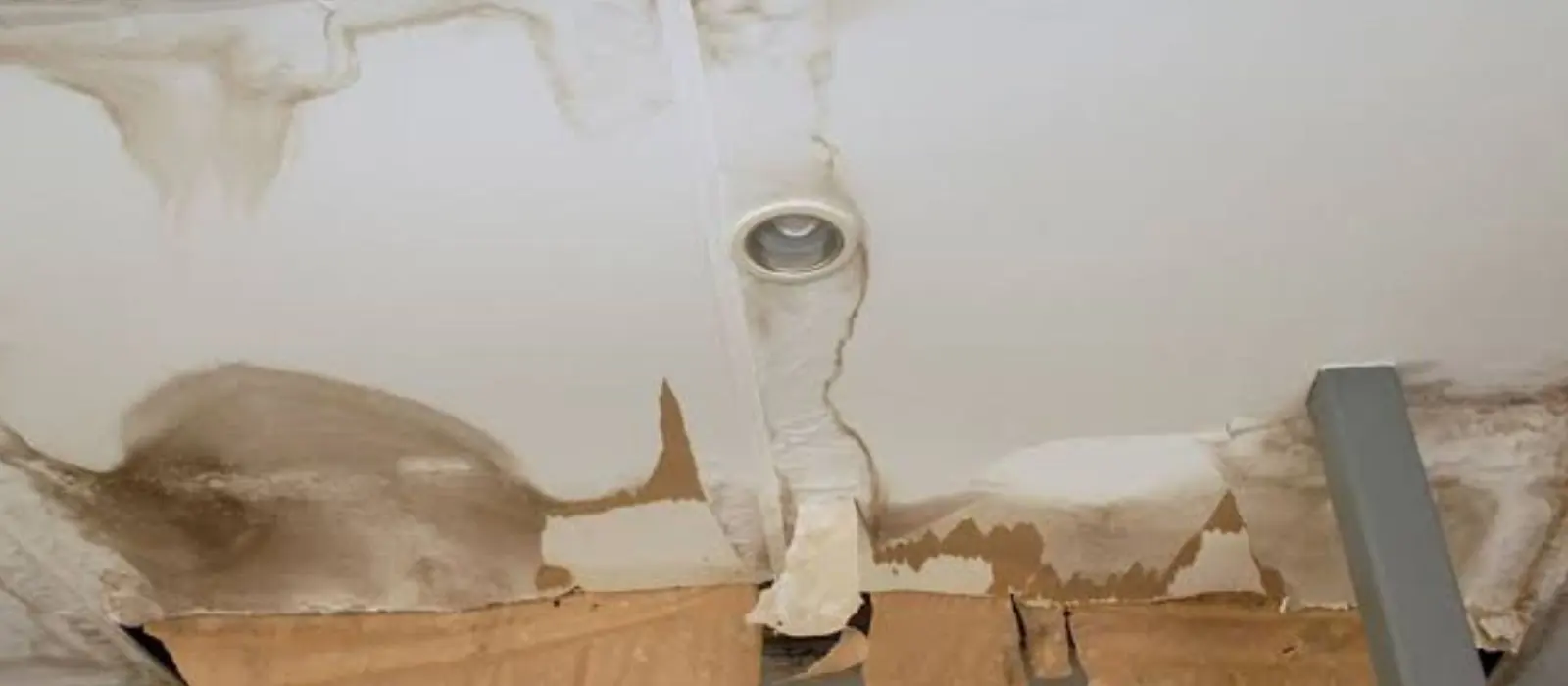 Brown water stain spreading across a ceiling around a light fixture