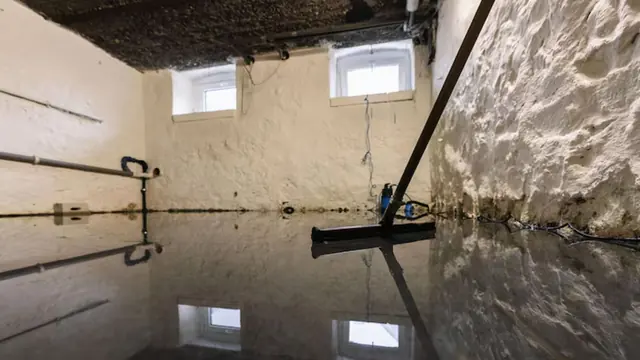 Flooded basement with a squeegee on the wet floor